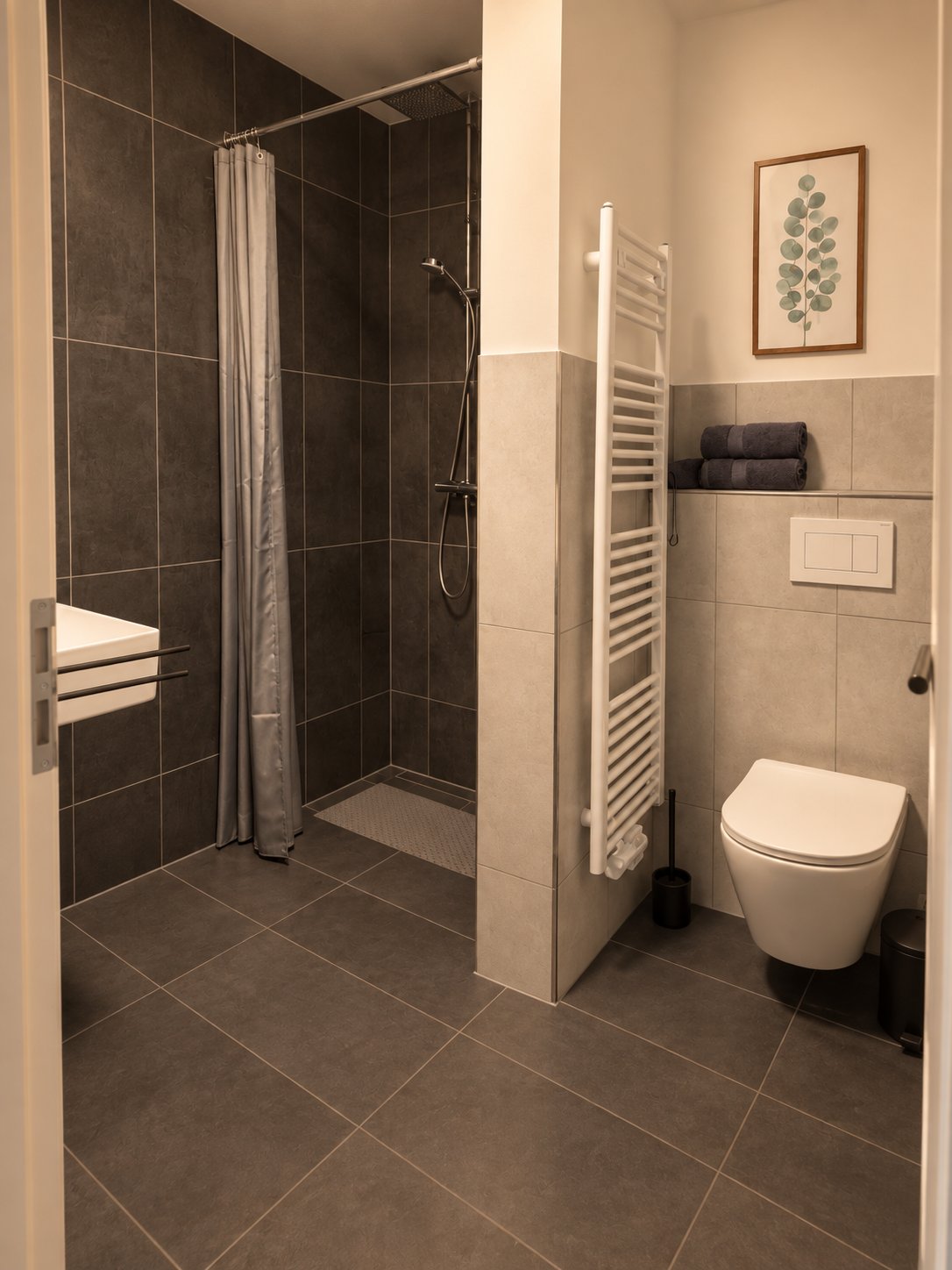 Bad eines Apartments mit bodengleicher Dusche und Wand-WC