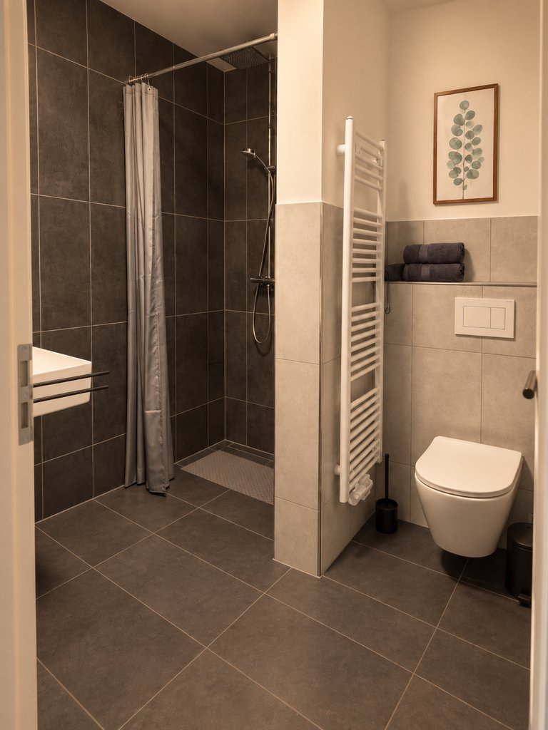 Bad eines Apartments mit bodengleicher Dusche und Wand-WC